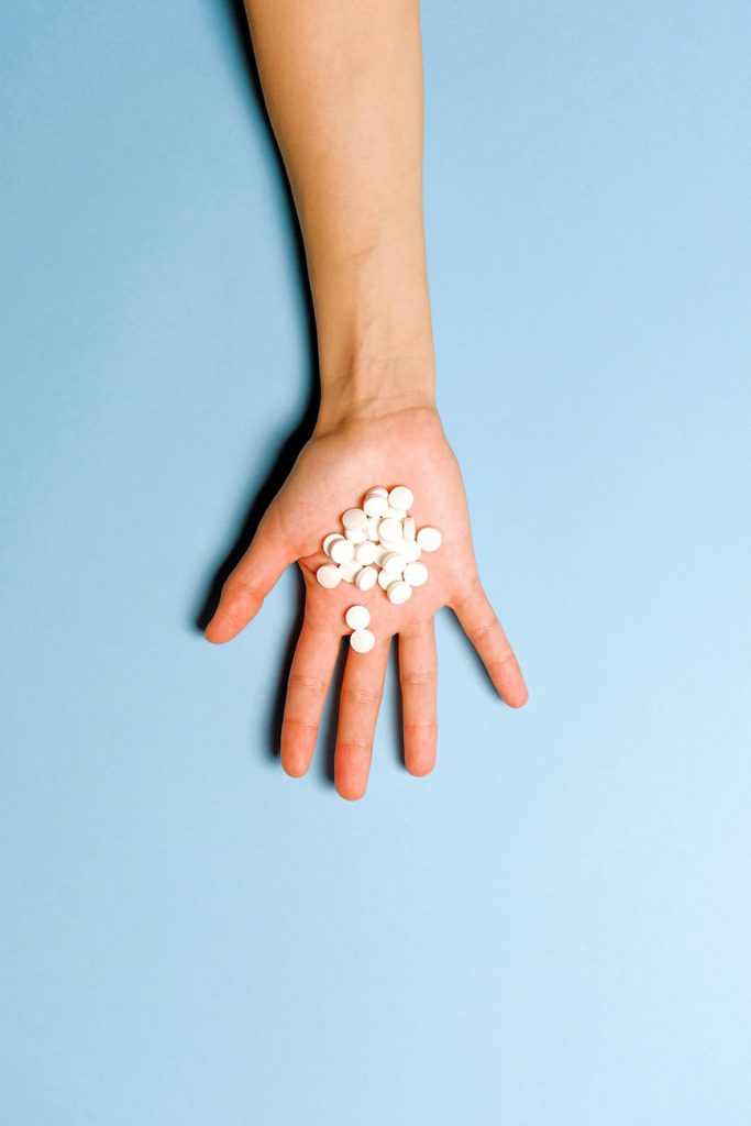 Tabletki Arthrotec na dłoni kobiety na błękitnym tle